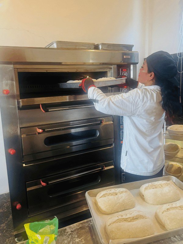 Baker sliding a tray of sourdough loaves into the deck oven